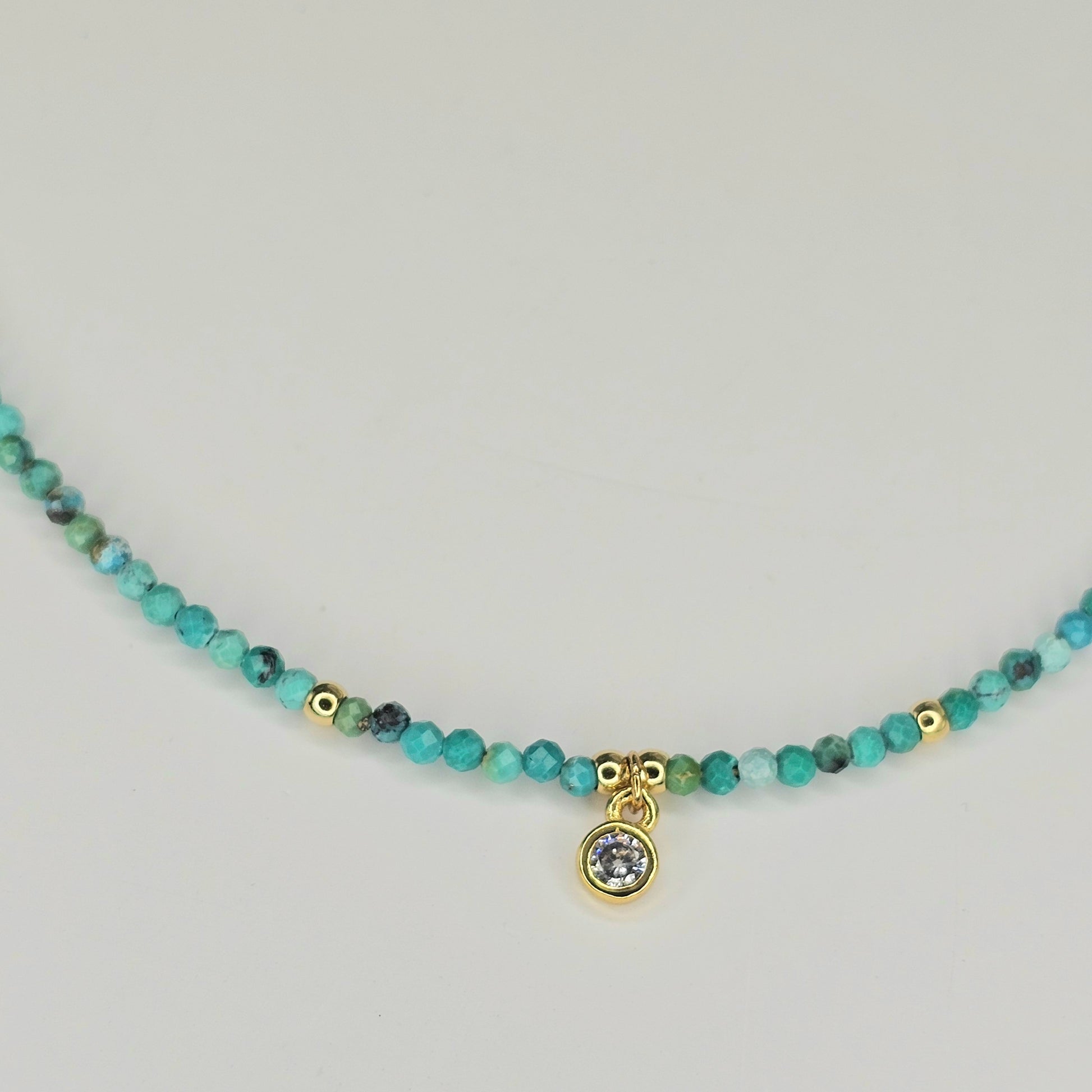 Delicate, faceted Turquoise bead necklace with an AAA grade CZ pendant and gold toned stainless steel clasp.