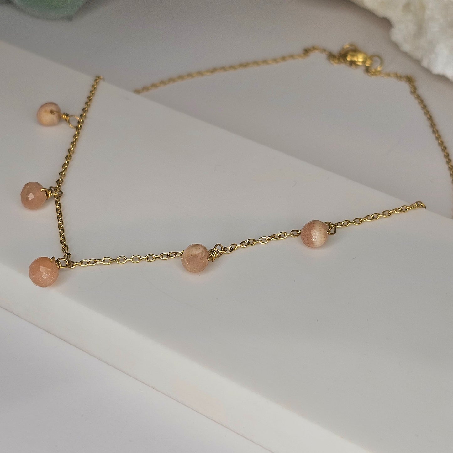 Fine gold toned stainless steel chain adorned with five dainty Sunstone beads.