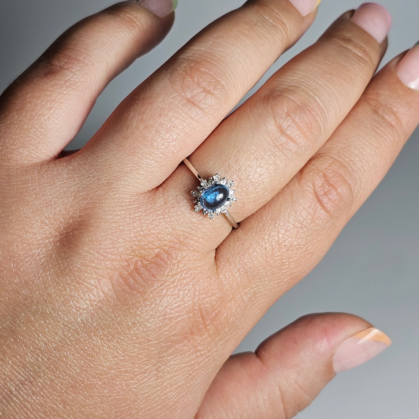 This adjustable floral burst ring is crafted from sterling silver and features a stunning oval shaped Swiss Blue Topaz centre stone surrounded with zircon.