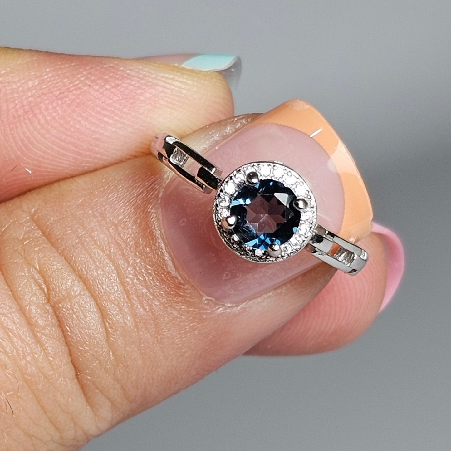 This adjustable ring is crafted from sterling silver and features a gorgeous round London Blue Topaz centre stone on a zircon prong setting crown, with link accented shoulder ring band.