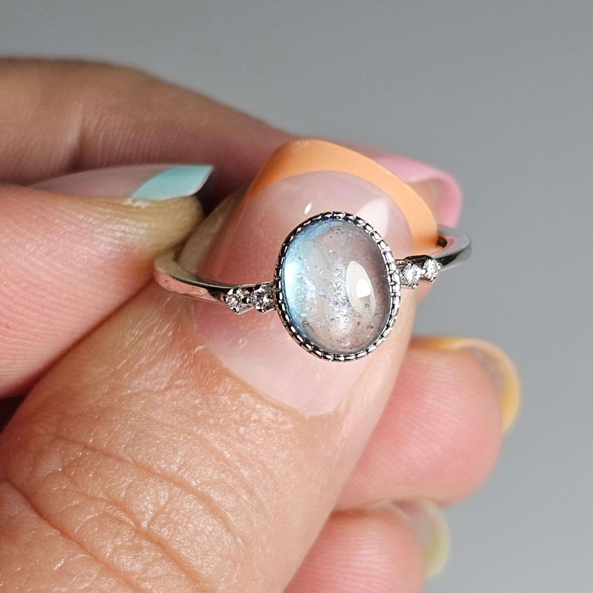 This adjustable ring is crafted from sterling silver and features a gorgeous oval Aquamarine with a Zircon accented shoulder ring band.