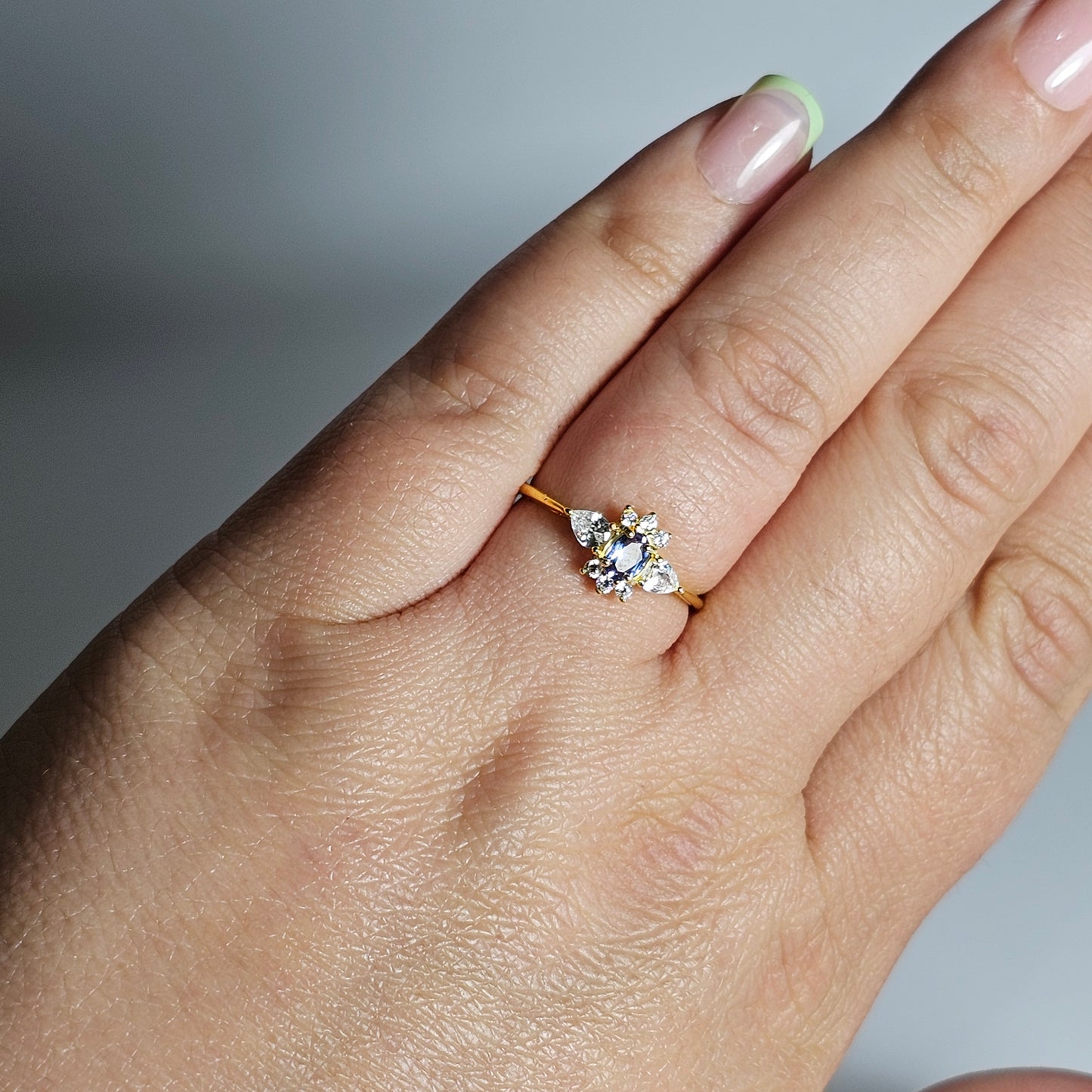 This adjustable ring is crafted from gold plated sterling silver and features a beautiful oval shaped Tanzanite centre stone surrounded with zircon.