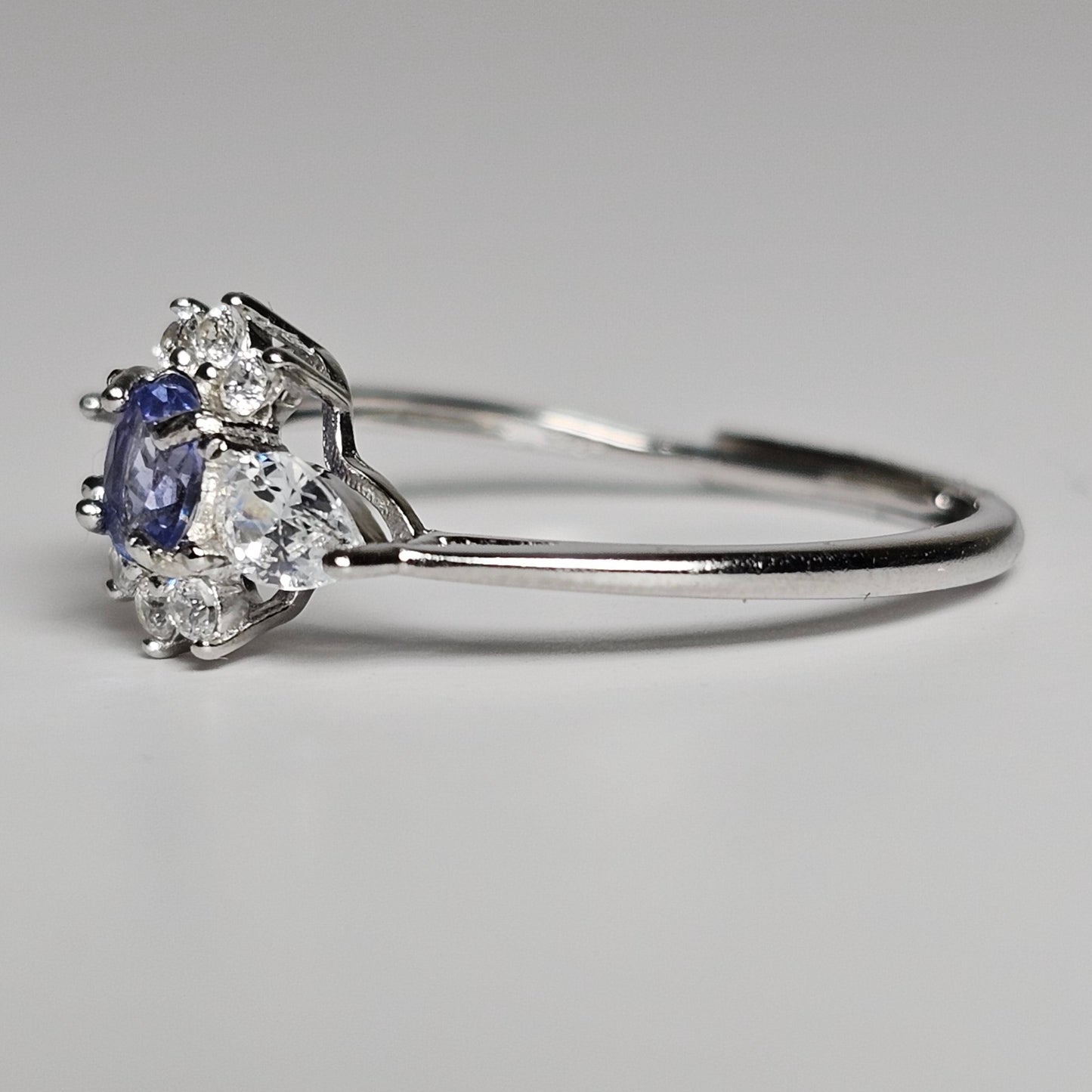 This adjustable ring is crafted from sterling silver and features a beautiful oval shaped Tanzanite centre stone surrounded with zircon.