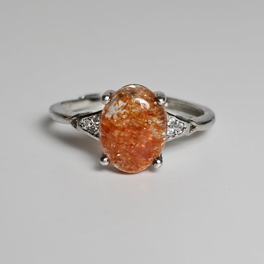 This adjustable ring is crafted from sterling silver and features a beautiful oval shaped Sunstone with zircon inlay shoulder ring band.