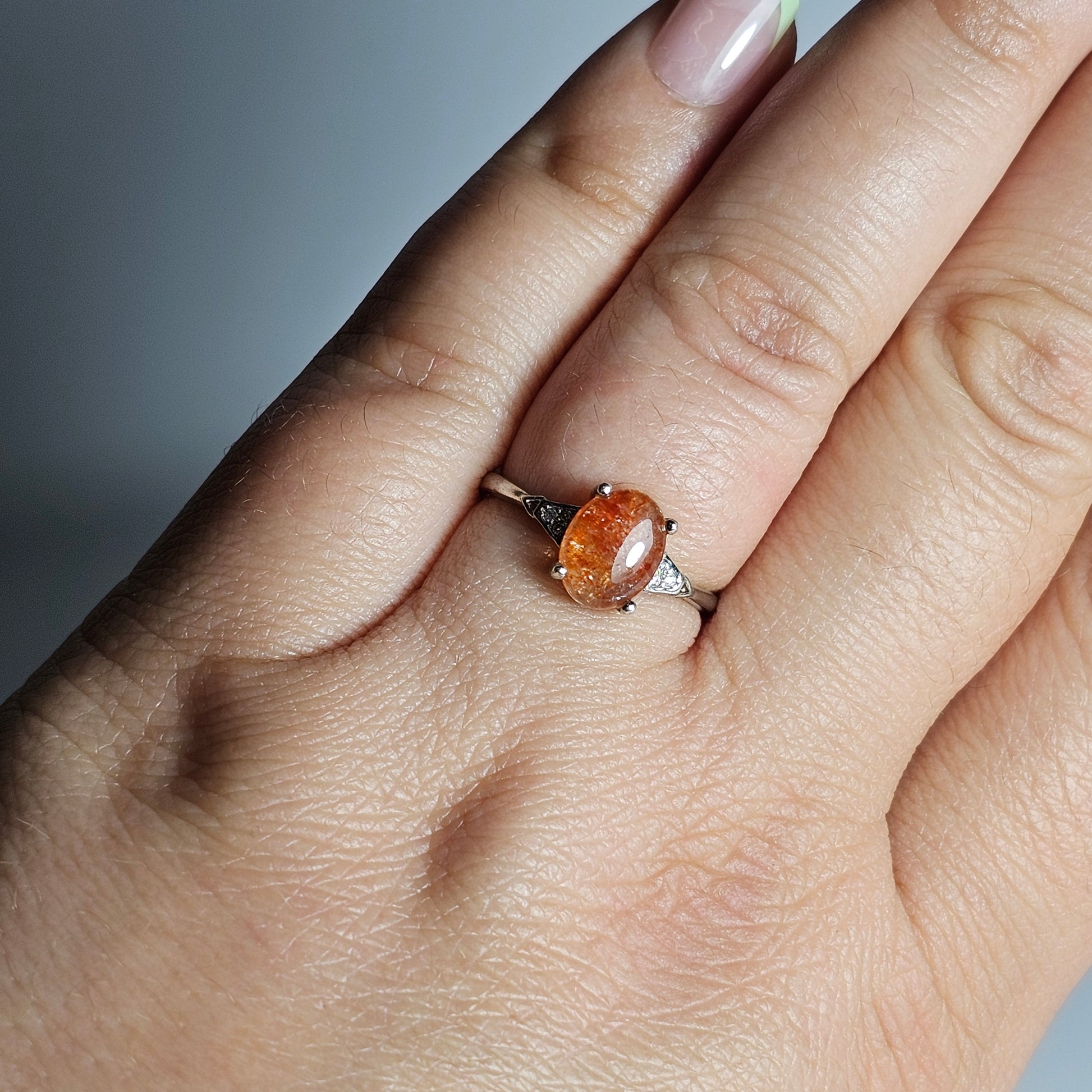 This adjustable ring is crafted from sterling silver and features a beautiful oval shaped Sunstone with zircon inlay shoulder ring band.