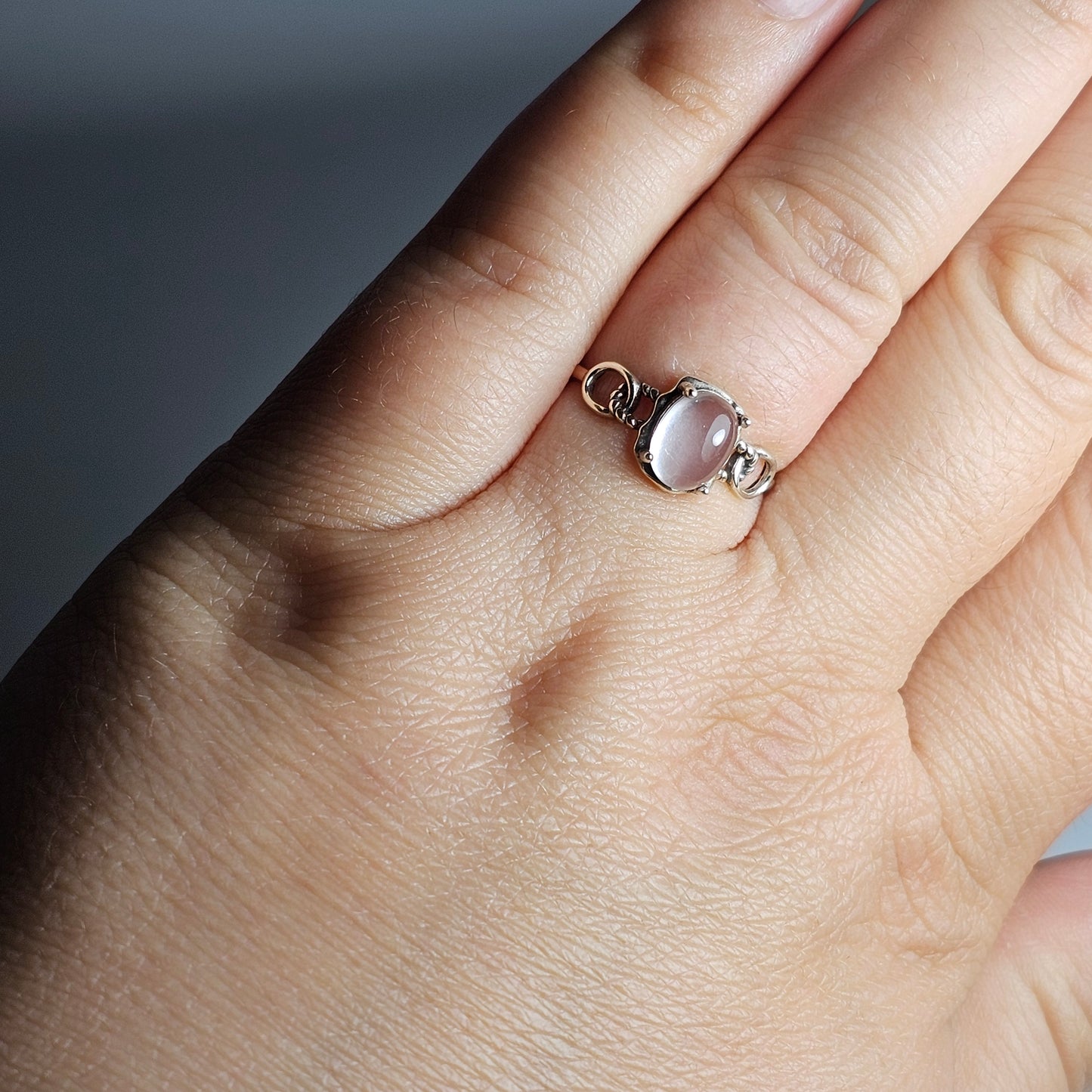 This adjustable ring is crafted from sterling silver and features an oval Star Rose Quartz with link accented shoulder ring band.