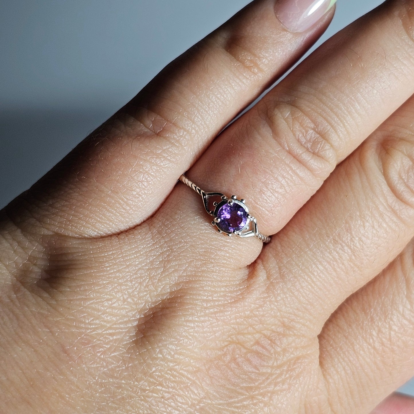 This adjustable fine ring is crafted from sterling silver and features a round Amethyst with heart and twist accented shoulder ring band.