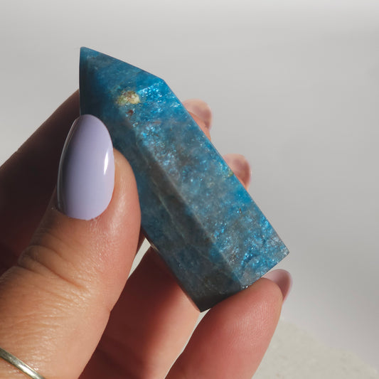 Blue Apatite tower held in hand showing size and natural flash in the stone.
