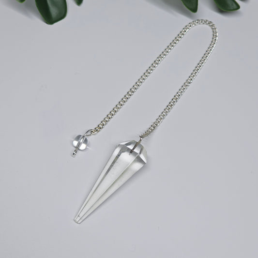 Close-up of a Clear Quartz pendulum featuring a polished crystal point, attached chain, and decorative bead, displayed on a flat surface.