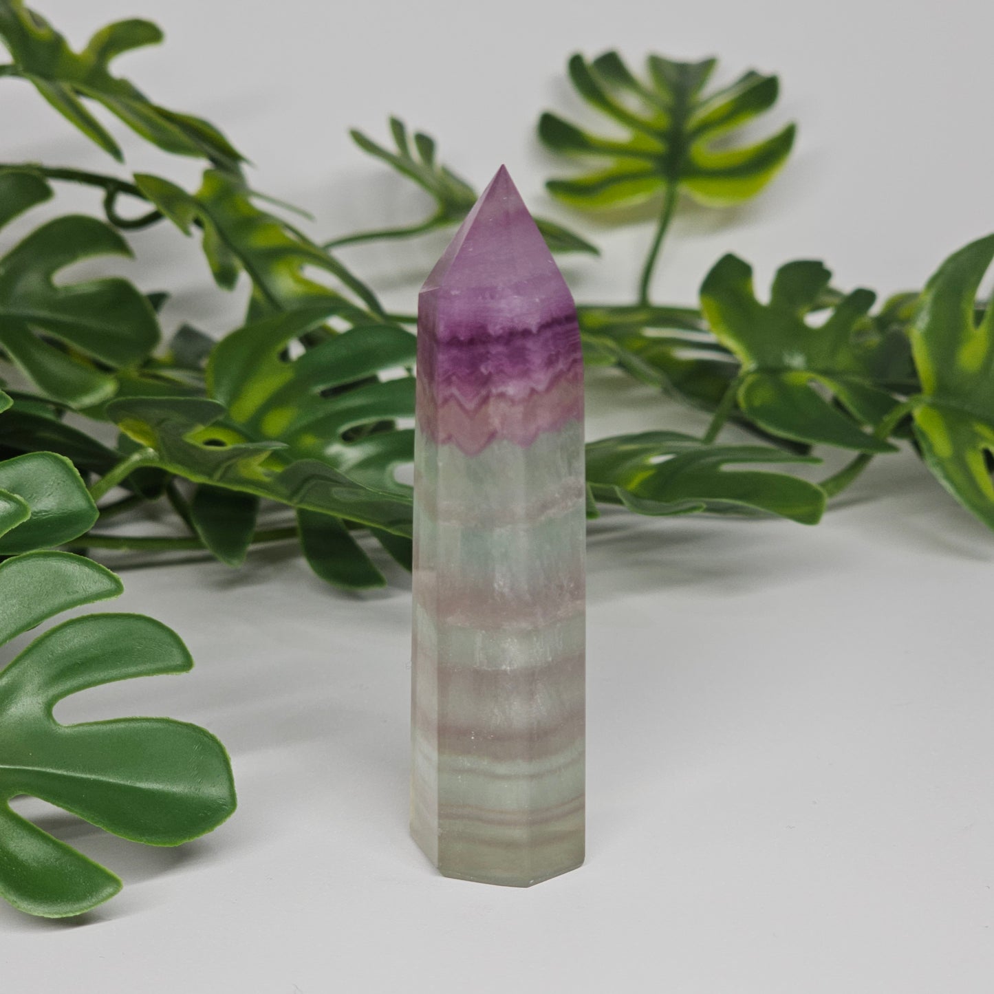 Fluorite crystal tower side profile showing layered banding with purple, green and yellow tones and polished finish