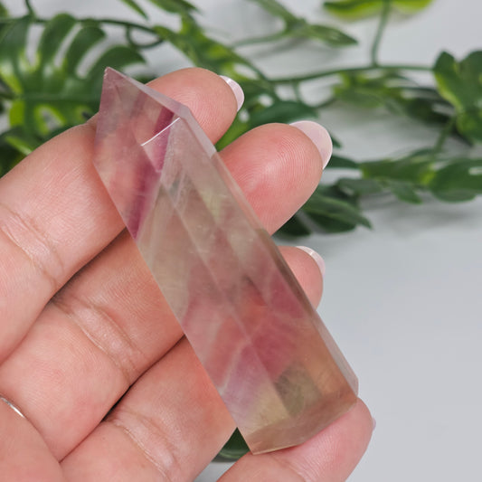 Fluorite crystal tower held in hand showing size with yellow, purple and green natural banding and polished point