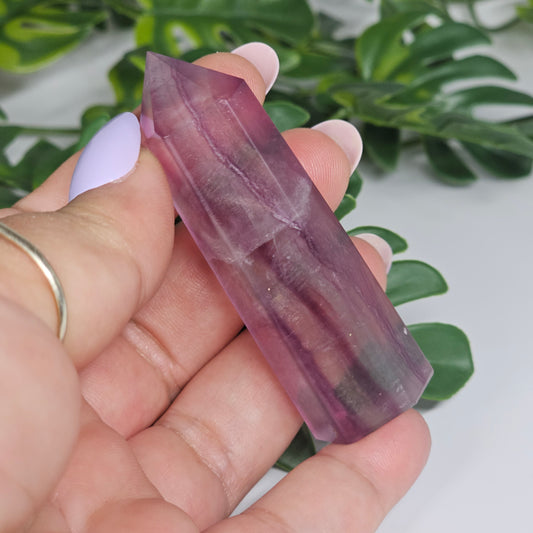 Fluorite crystal tower held in hand showing size with yellow, purple and green natural banding and polished point