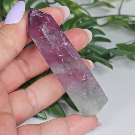 Fluorite crystal tower held in hand showing size with yellow, purple and green natural banding and polished point