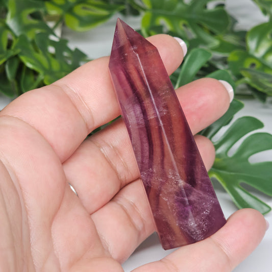 Fluorite crystal tower held in hand showing size with yellow, purple and green natural banding and polished point
