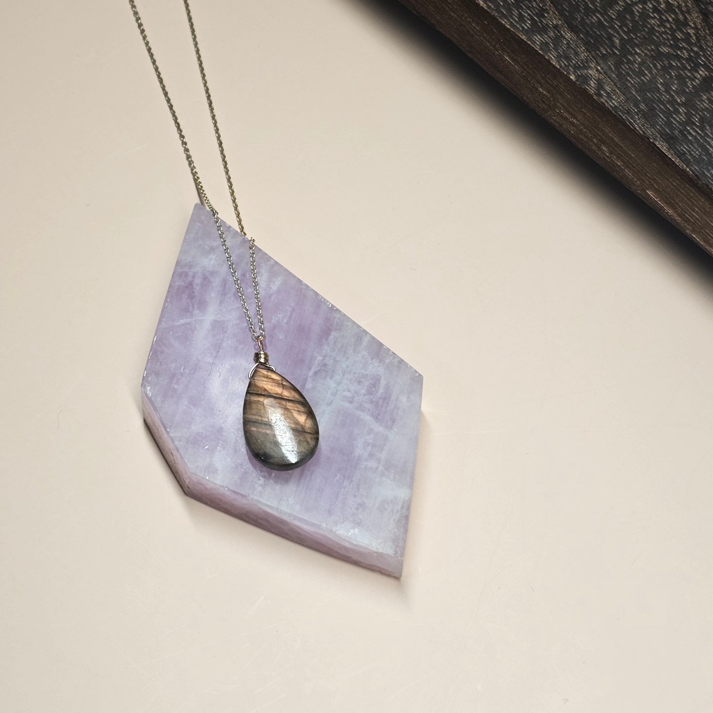 Kunzite slab used as a backdrop for necklace styling, enhancing jewellery presentation with soft pink lilac tones.