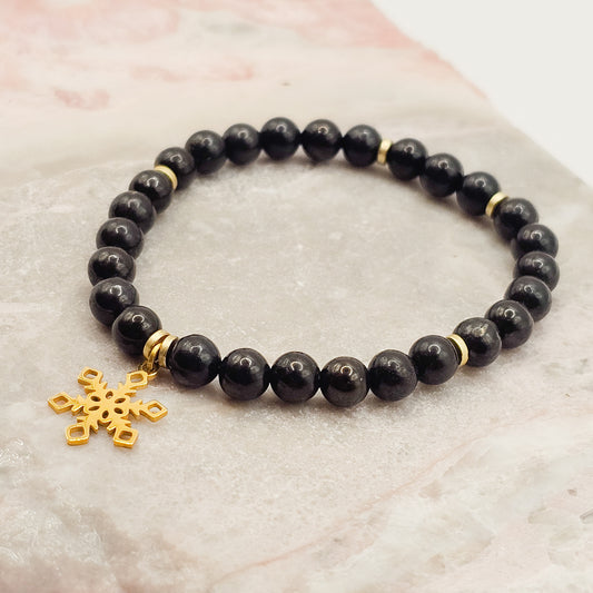 Shungite and Hematite stretch bracelet with golden stainless steel snowflake charm | When worn, Shungite is said to emit pain-killing properties and helps fight fatigue.