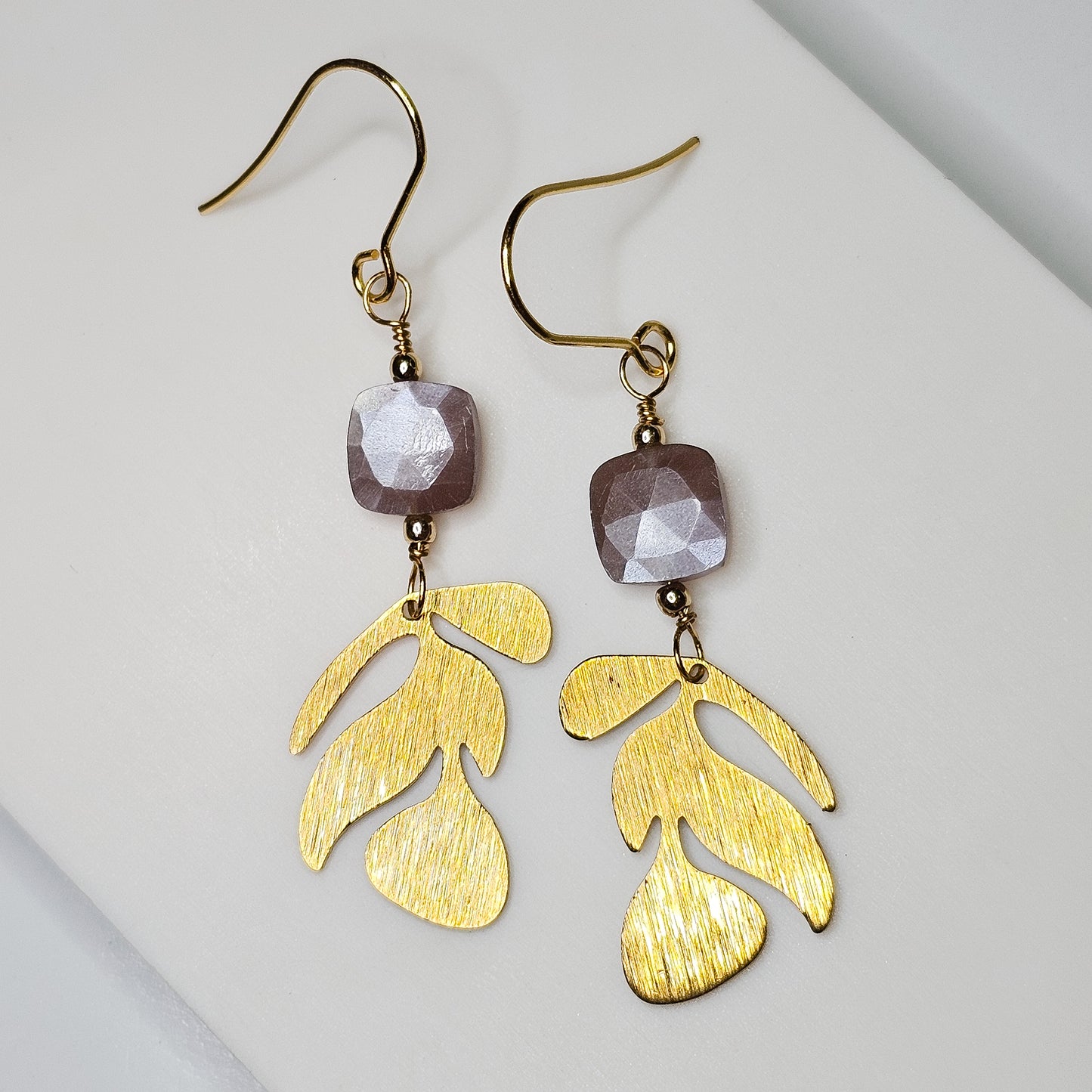 Brushed brass leaf charms suspended from silver flash Chocolate Moonstones beads, hanging from gold toned stainless steel ear wires.