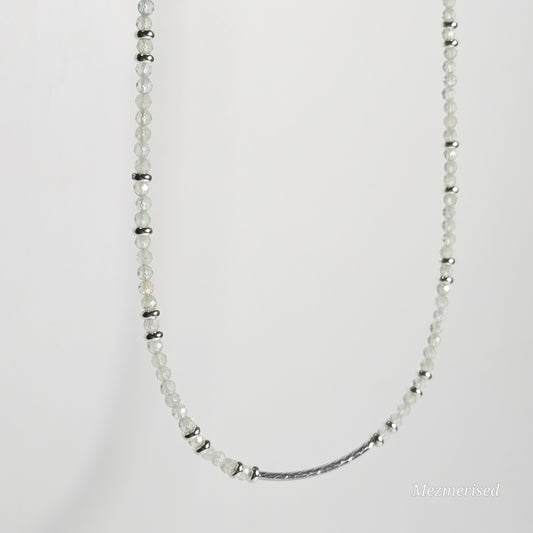 Side angle of Prehnite necklace hanging, highlighting curved bar accent and natural drape of beads.