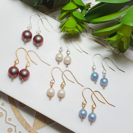 Genuine Swarovski Pearl earrings with Iron ear wires in 8mm Iridescent Red, 6mm Pearlescent White and 6mm Iridescent light blue. Comes in gold and silver.