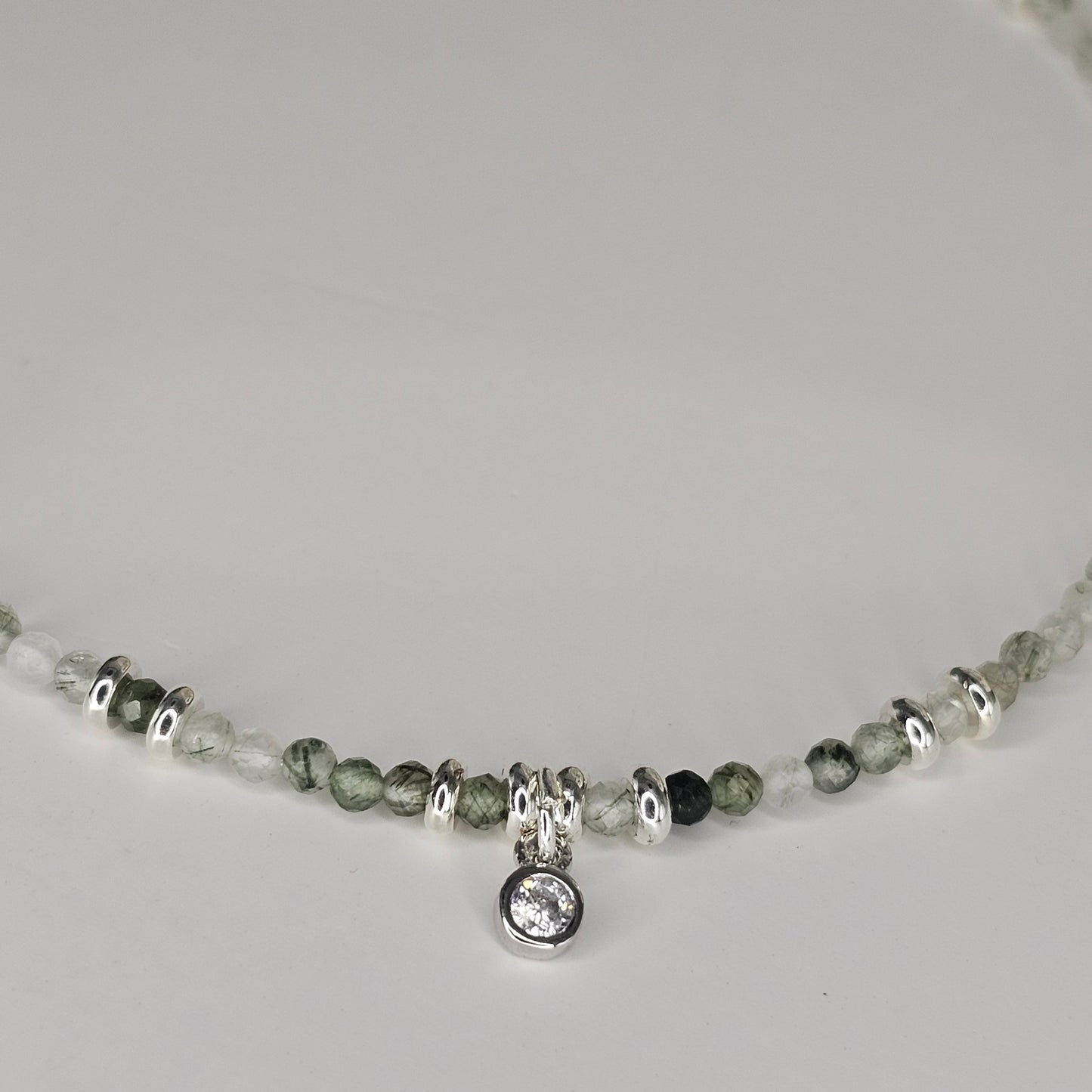 Delicate, faceted Green Rutile Quartz bead necklace with an AAA grade CZ pendant and silver toned stainless steel clasp.