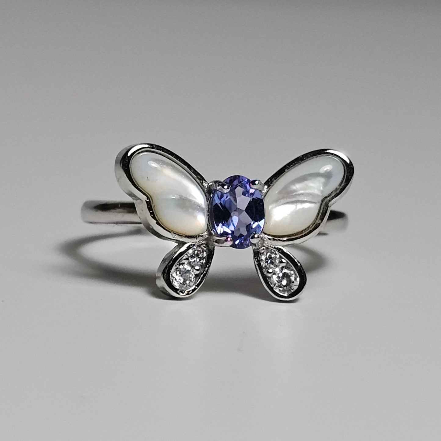 Adjustable sterling silver ring features a butterfly design with a stunning Tanzanite, shell and zircons.