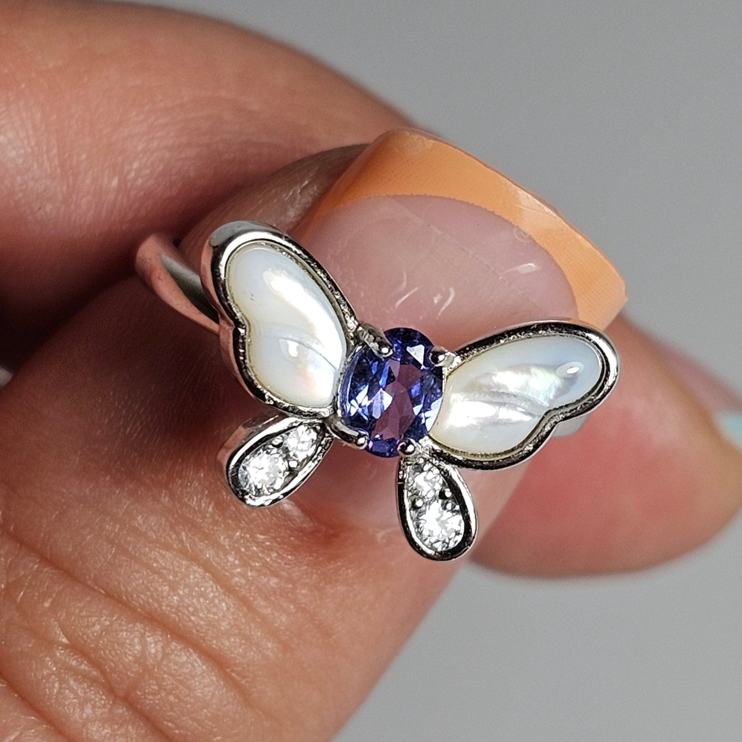 Adjustable sterling silver ring features a butterfly design with a stunning Tanzanite, shell and zircons.