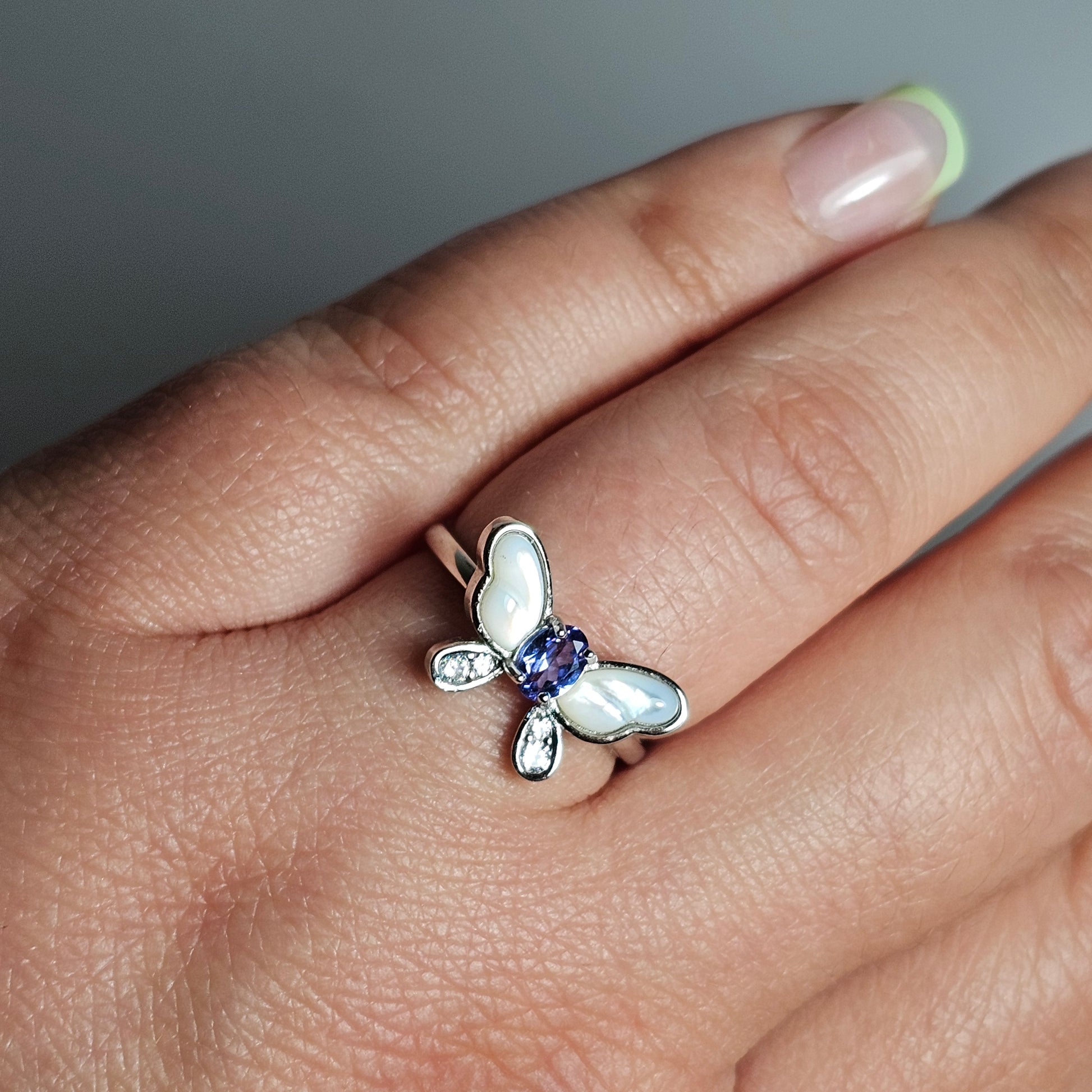 Adjustable sterling silver ring features a butterfly design with a stunning Tanzanite, shell and zircons.