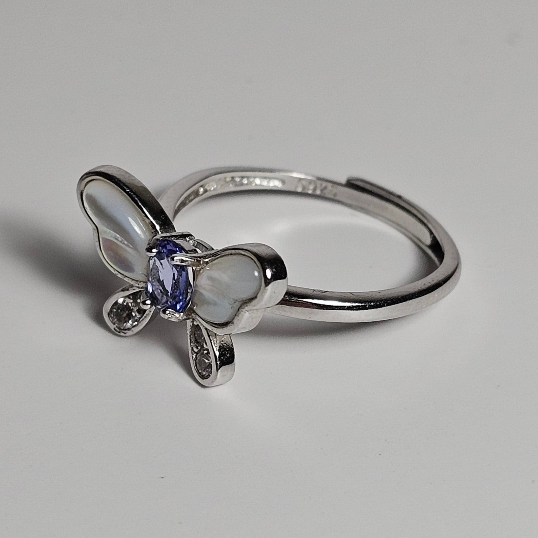 Adjustable sterling silver ring features a butterfly design with a stunning Tanzanite, shell and zircons.