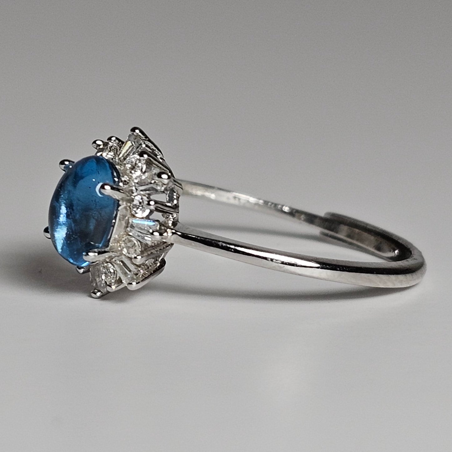 This adjustable floral burst ring is crafted from sterling silver and features a stunning oval shaped Swiss Blue Topaz centre stone surrounded with zircon.