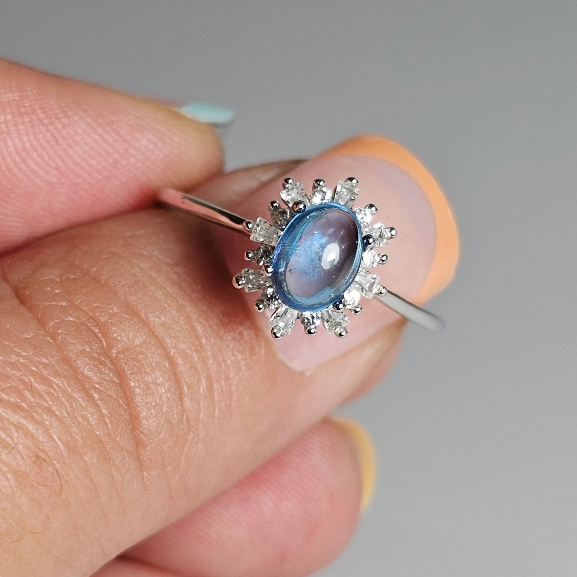 This adjustable floral burst ring is crafted from sterling silver and features a stunning oval shaped Swiss Blue Topaz centre stone surrounded with zircon.