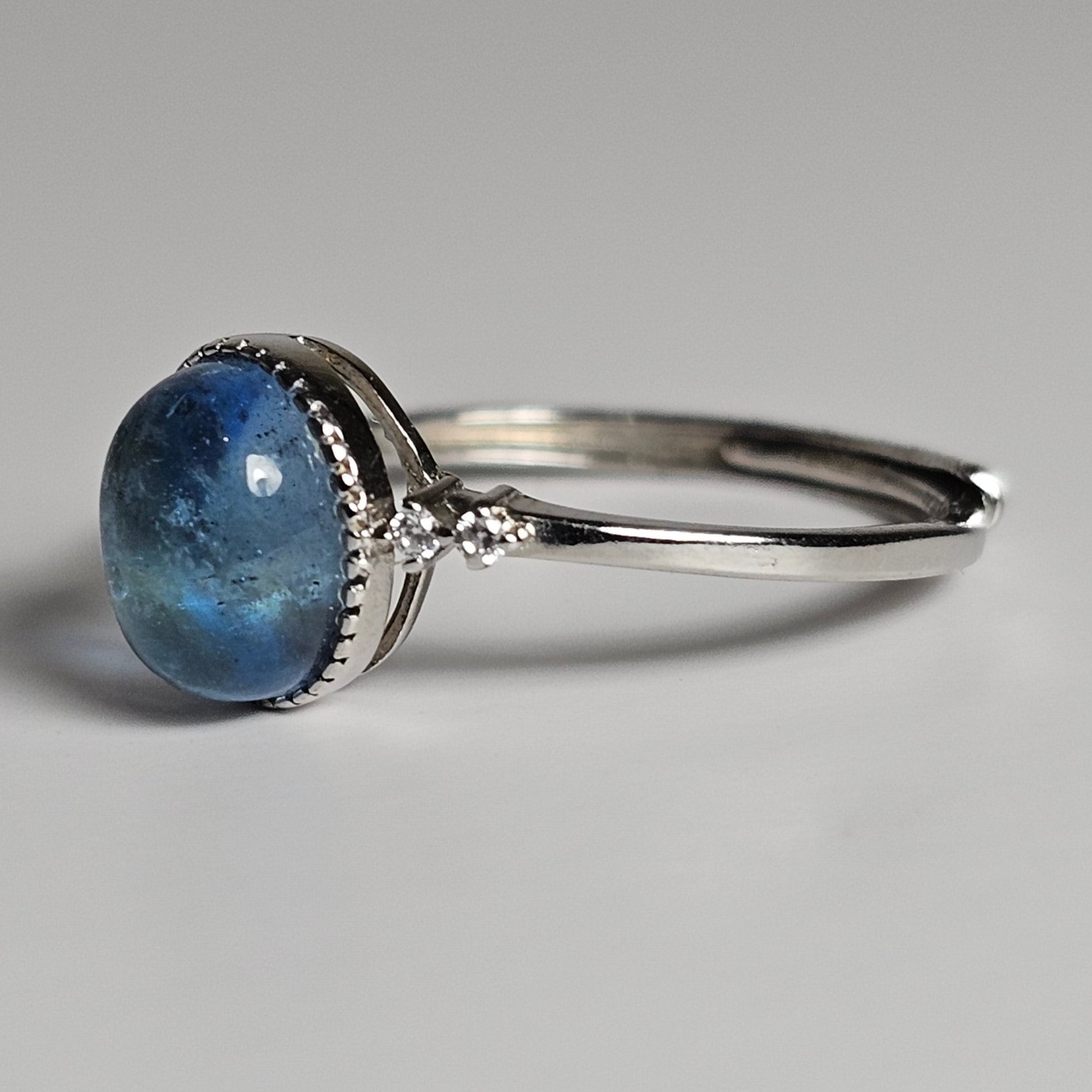 This adjustable ring is crafted from sterling silver and features a gorgeous oval Aquamarine with a Zircon accented shoulder ring band.