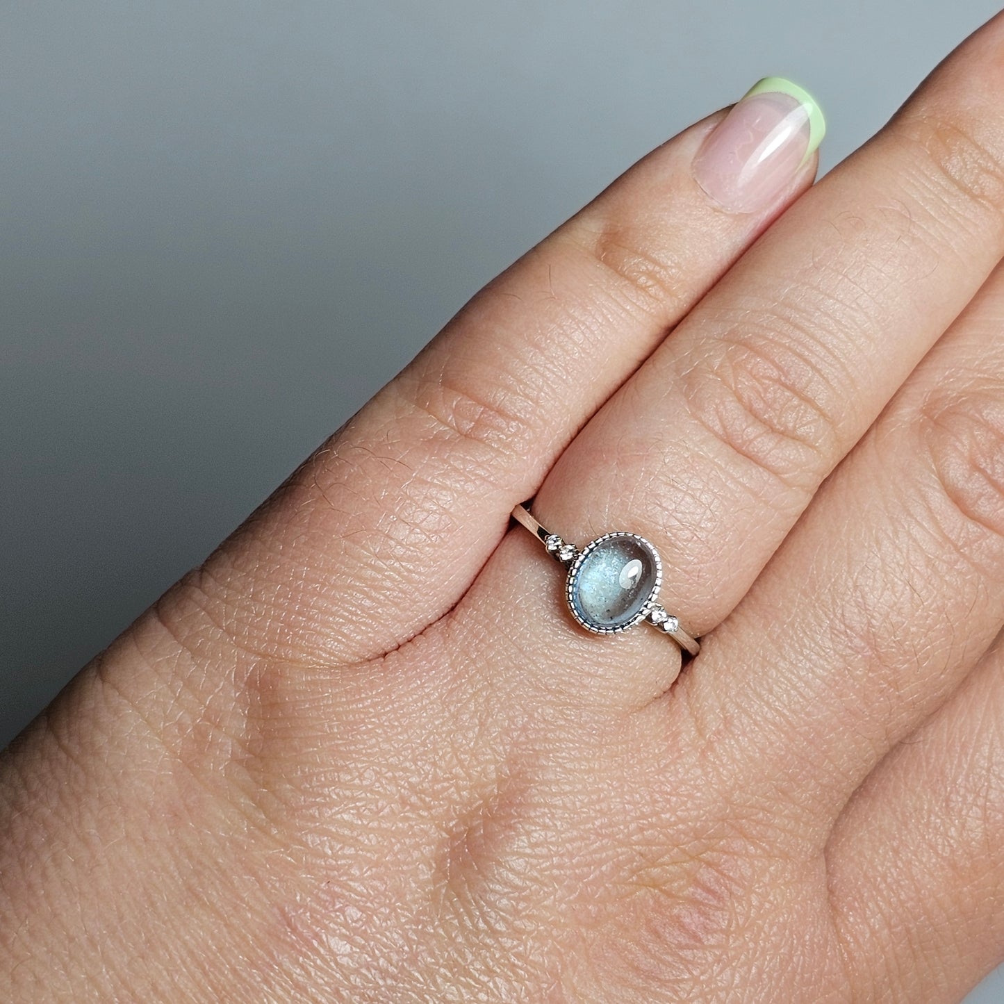 This adjustable ring is crafted from sterling silver and features a gorgeous oval Aquamarine with a Zircon accented shoulder ring band.