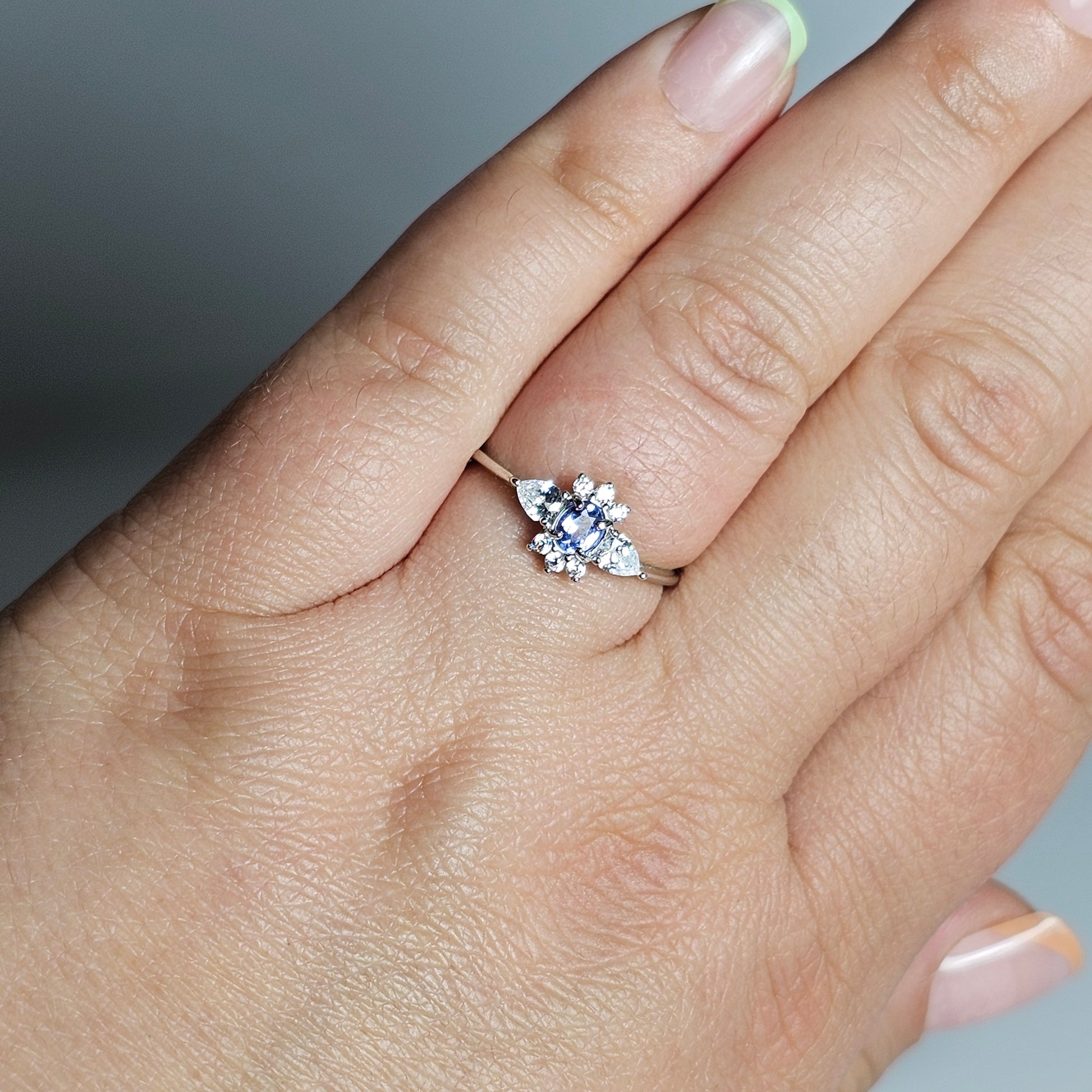 This adjustable ring is crafted from sterling silver and features a beautiful oval shaped Tanzanite centre stone surrounded with zircon.