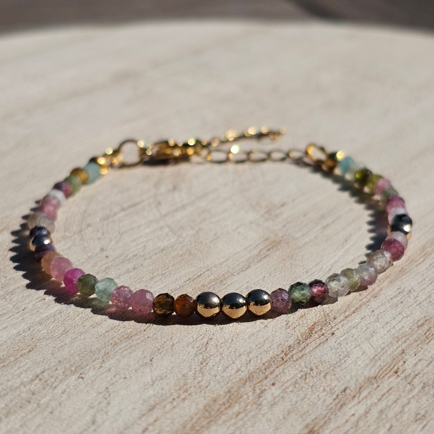 Delicate, faceted dainty AA grade colourful Tourmaline and AAA grade gold plated Hematite bead bracelet with a gold stainless steel clasp and extender chain.