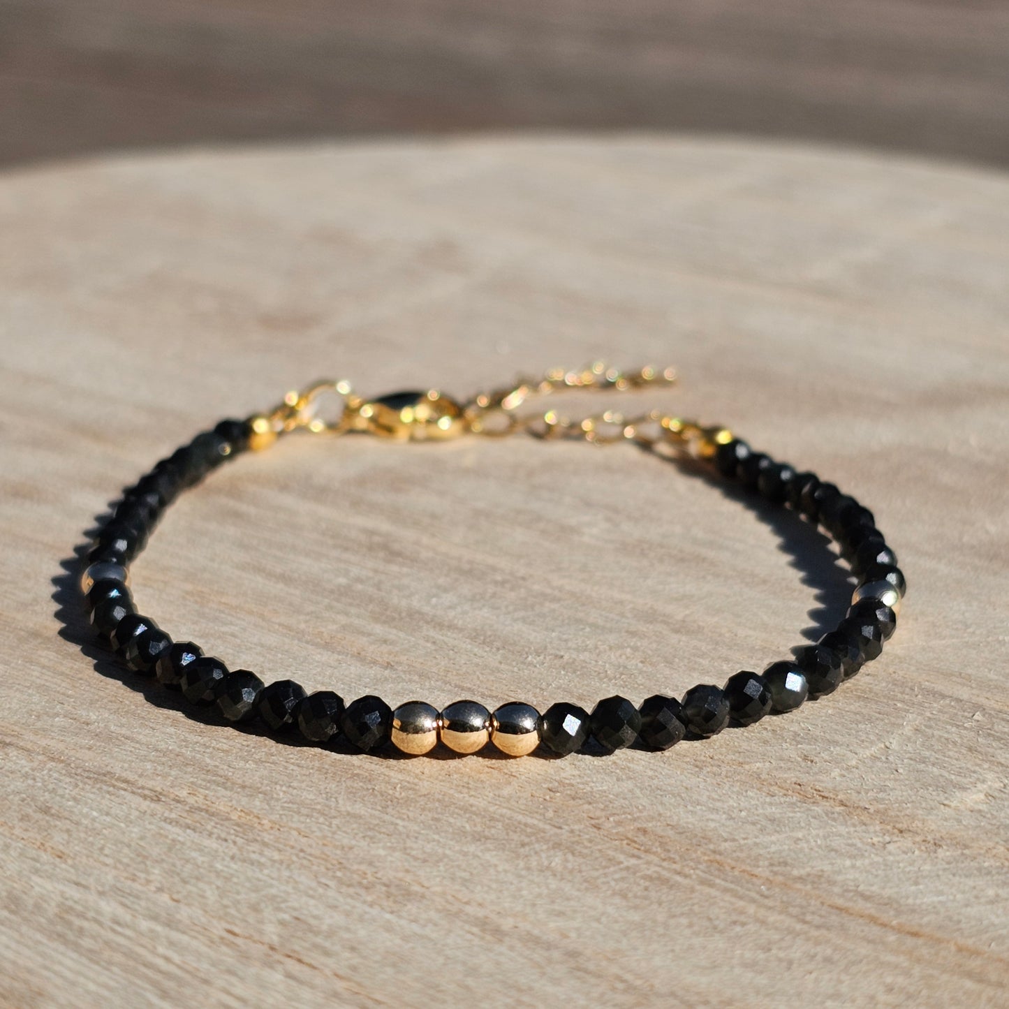 Delicate, faceted dainty Obsidian and AAA grade gold plated Hematite bead bracelet with a gold stainless steel clasp and extender chain.