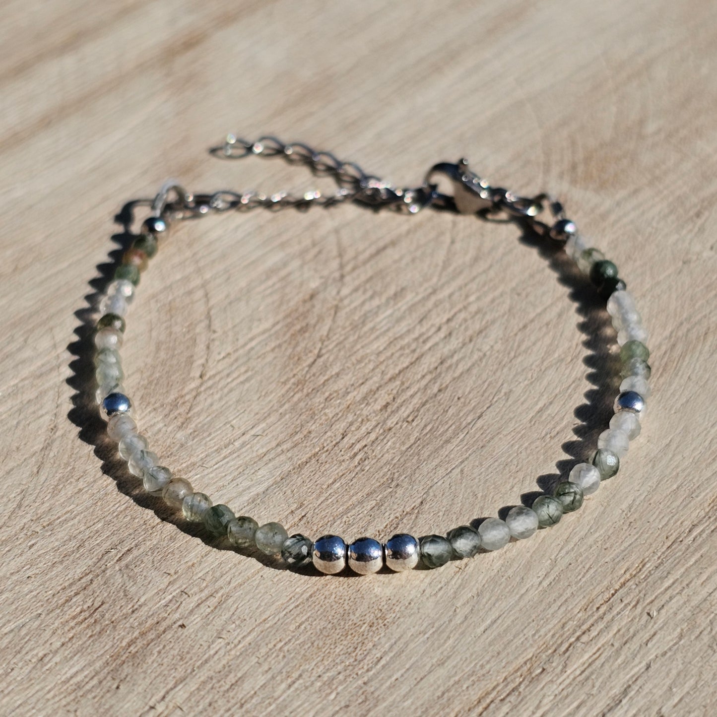 Delicate, faceted dainty green Rutile Quartz and AAA grade silver plated Hematite bead bracelet with a silver stainless steel clasp and extender chain.