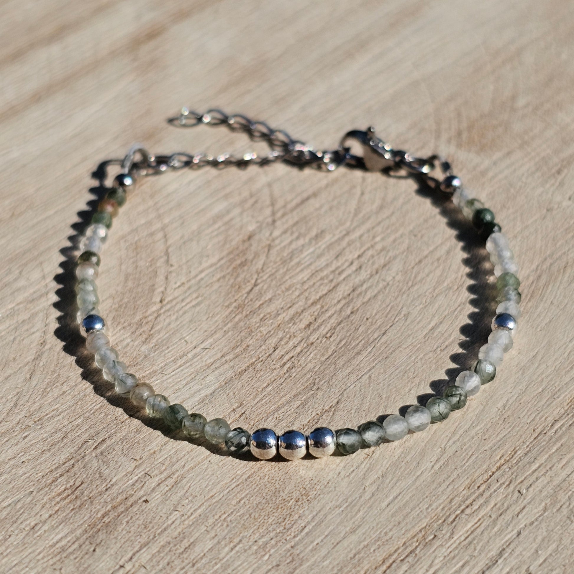 Delicate, faceted dainty green Rutile Quartz and AAA grade silver plated Hematite bead bracelet with a silver stainless steel clasp and extender chain.