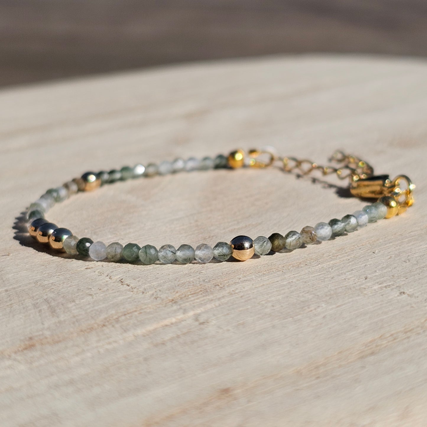 Delicate, faceted dainty green Rutile Quartz and AAA grade gold plated Hematite bead bracelet with a gold stainless steel clasp and extender chain.