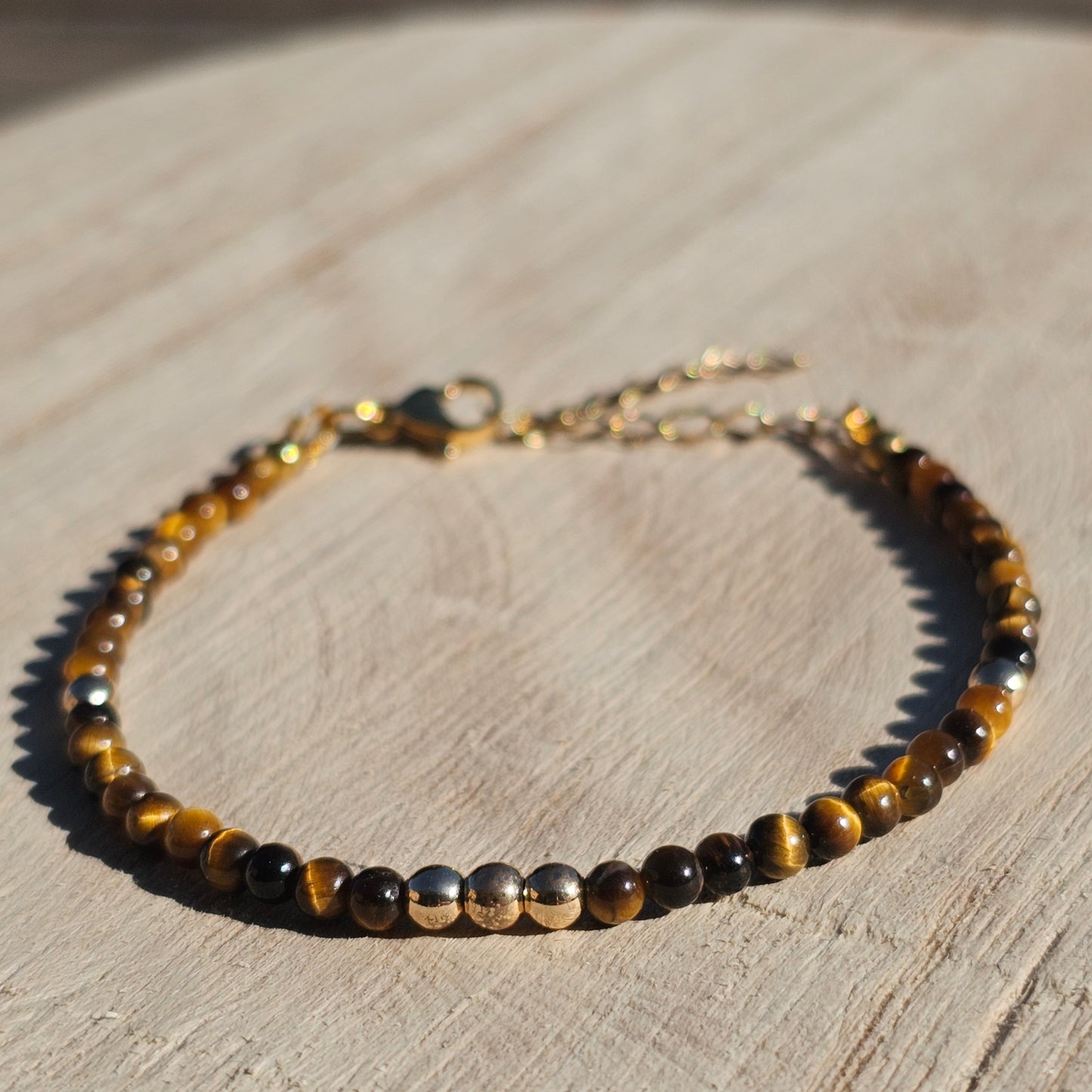 Delicate, round dainty AA Grade Tigers Eye and AAA grade gold plated Hematite bead bracelet with a gold stainless steel clasp and extender chain.