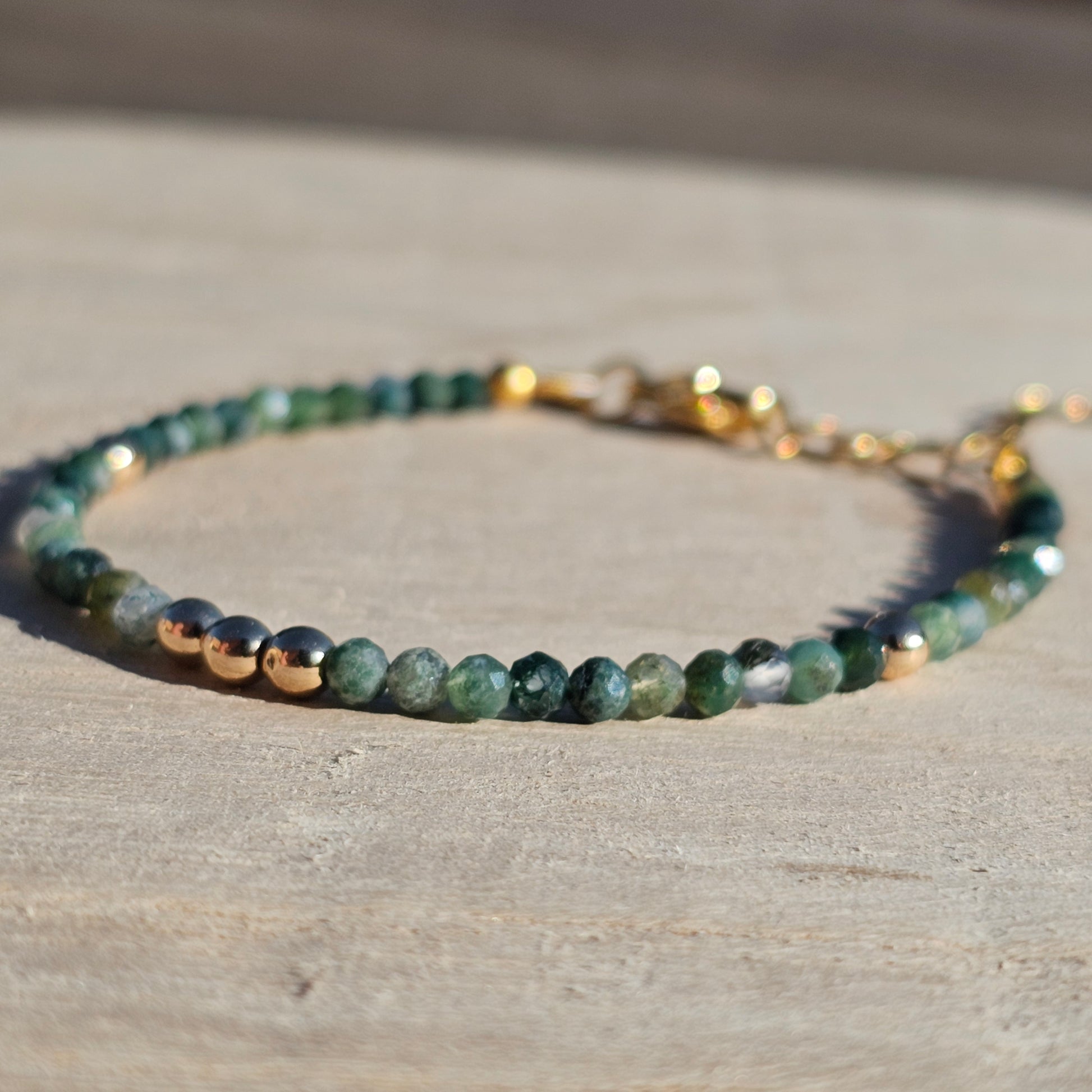 Delicate, faceted dainty Moss Agate and AAA grade gold plated Hematite bead bracelet with a gold stainless steel clasp and extender chain.