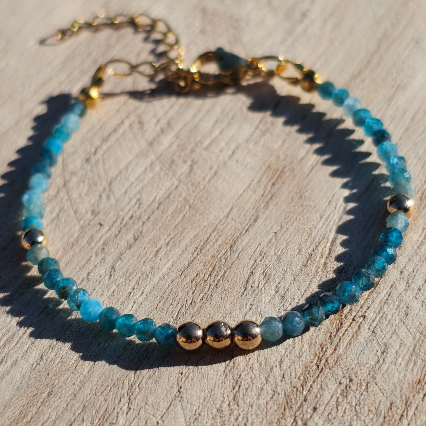 Delicate, faceted dainty AA grade Blue Apatite and AAA grade gold plated Hematite bead bracelet with a gold stainless steel clasp and extender chain.