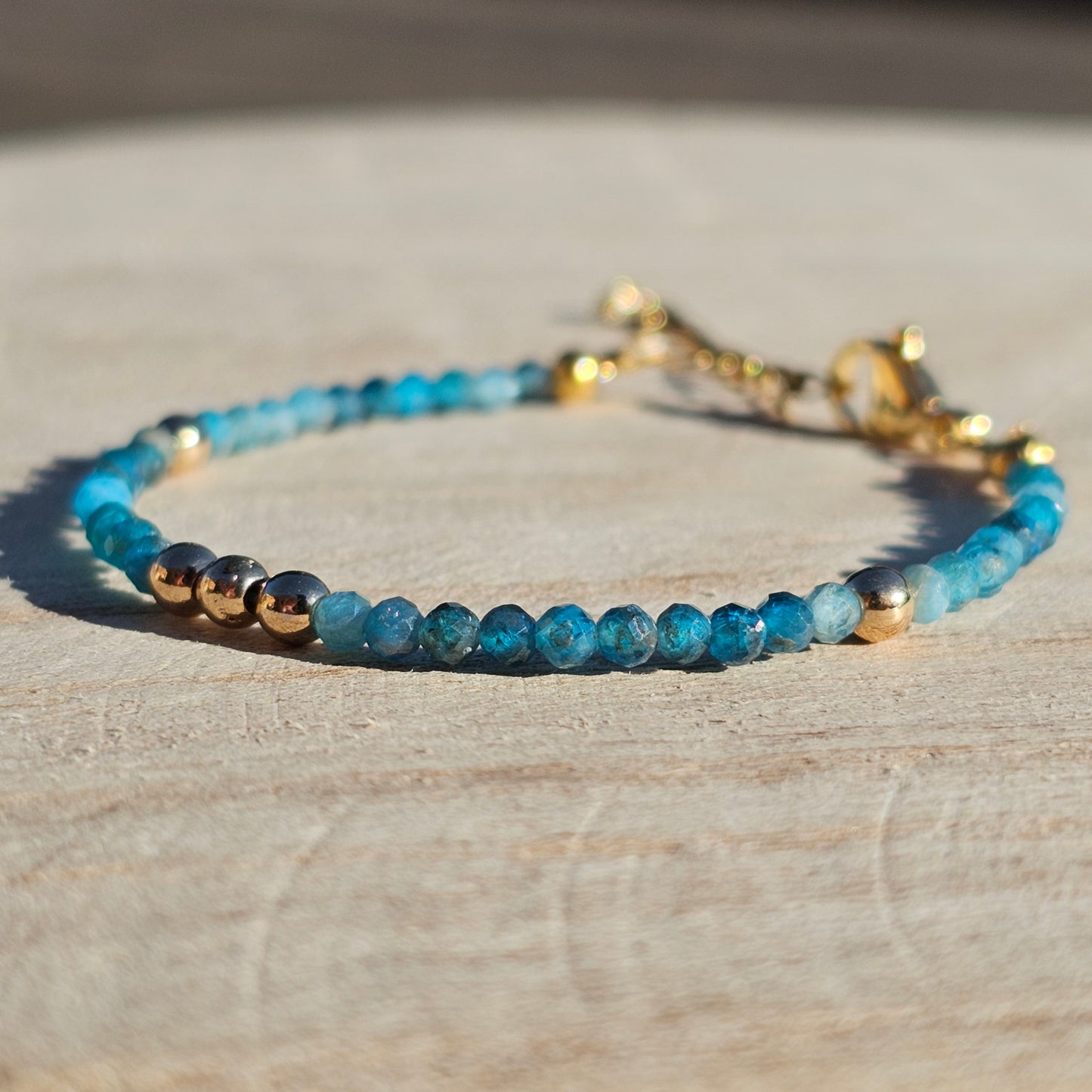 Delicate, faceted dainty AA grade Blue Apatite and AAA grade gold plated Hematite bead bracelet with a gold stainless steel clasp and extender chain.