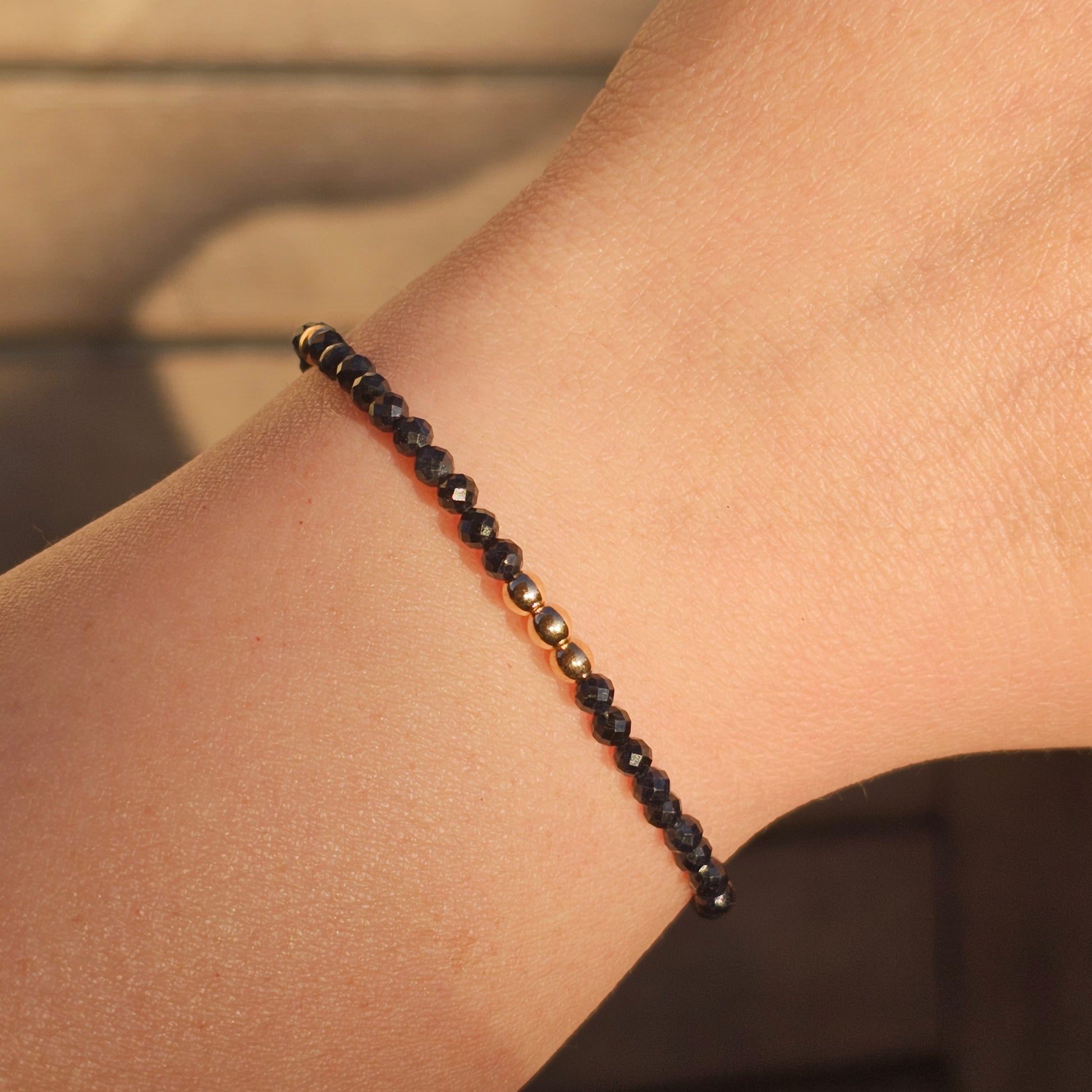 Delicate, faceted dainty Obsidian and AAA grade gold plated Hematite bead bracelet with a gold stainless steel clasp and extender chain.