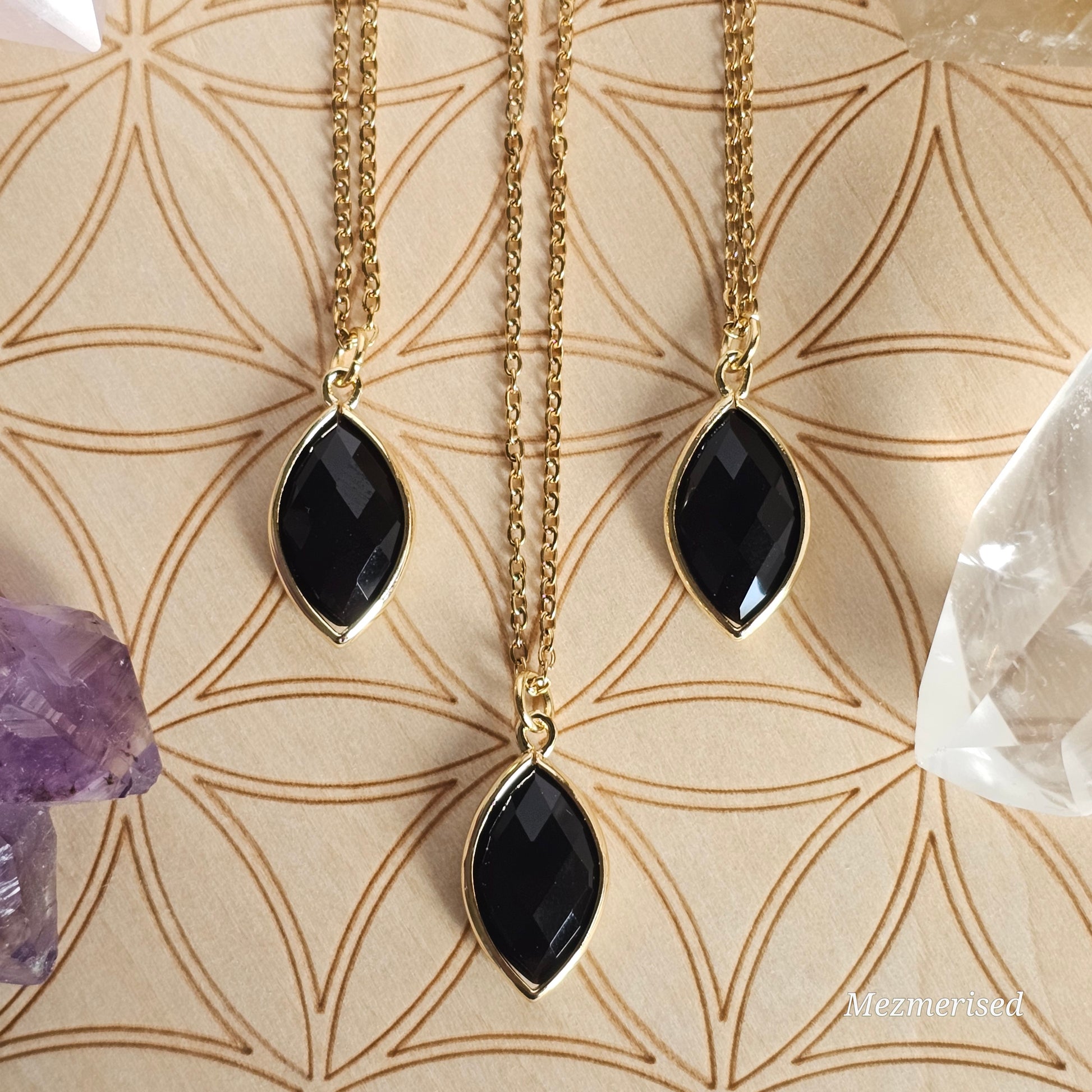 Faceted Onyx marquise pendant suspended from a gold coloured stainless steel chain.