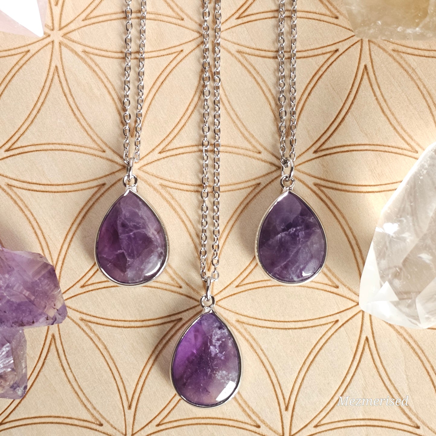 Faceted Amethyst teardrop pendant suspended from a silver coloured stainless steel chain.