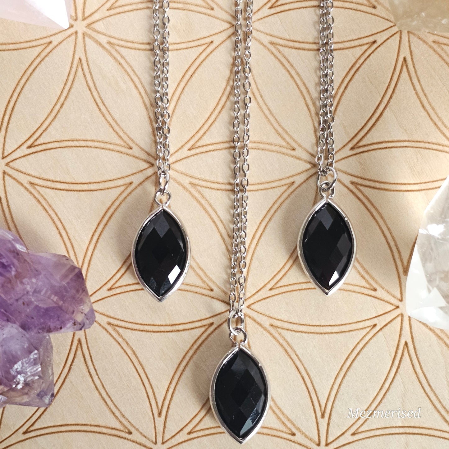 Faceted Onyx marquise pendant suspended from a silver coloured stainless steel chain.