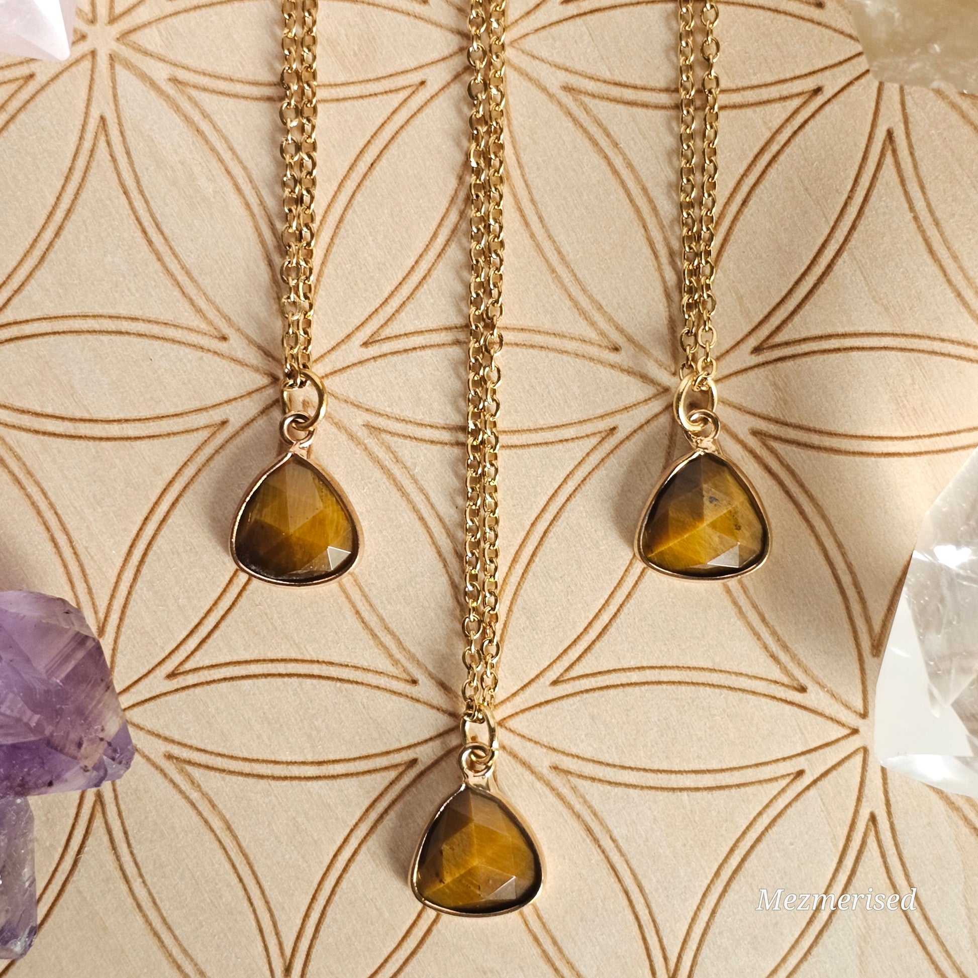 Faceted Tiger's Eye trillion pendant suspended from a gold coloured stainless steel chain.