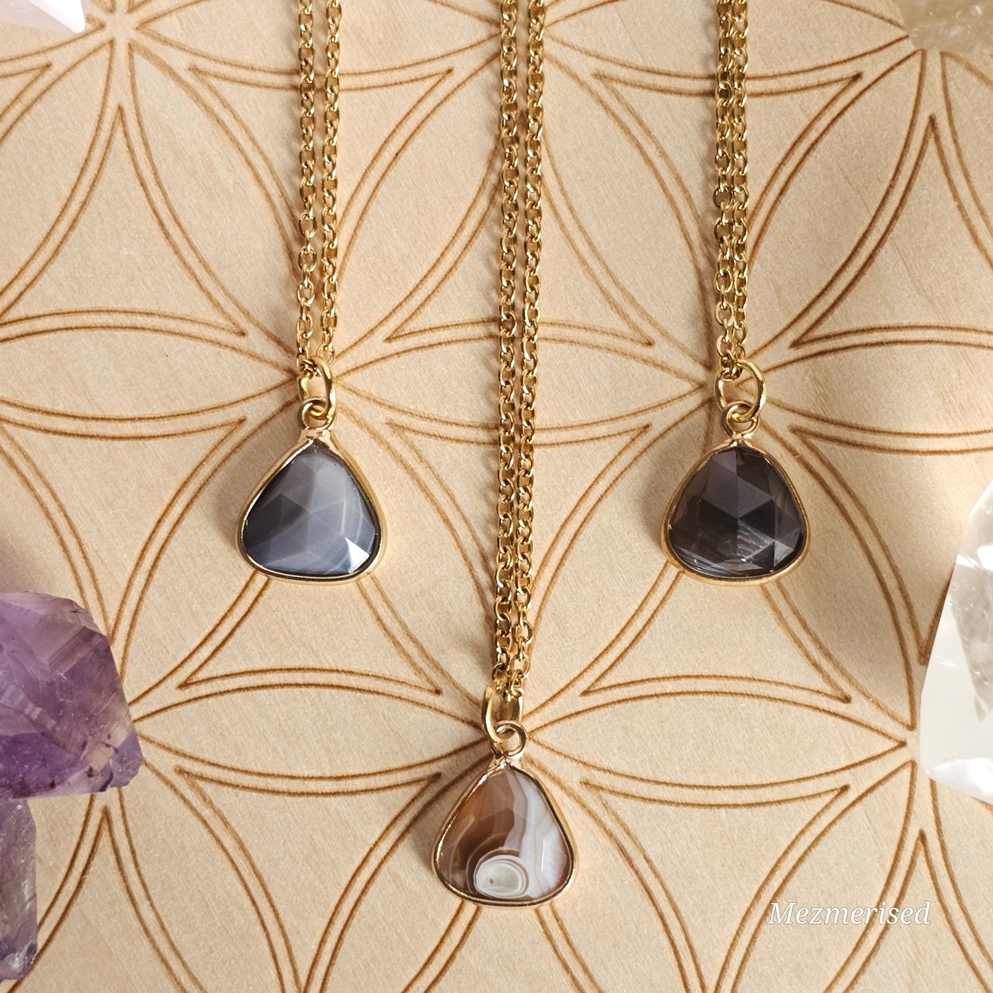 Faceted Botswana Agate trillion pendant suspended from a gold coloured stainless steel chain.