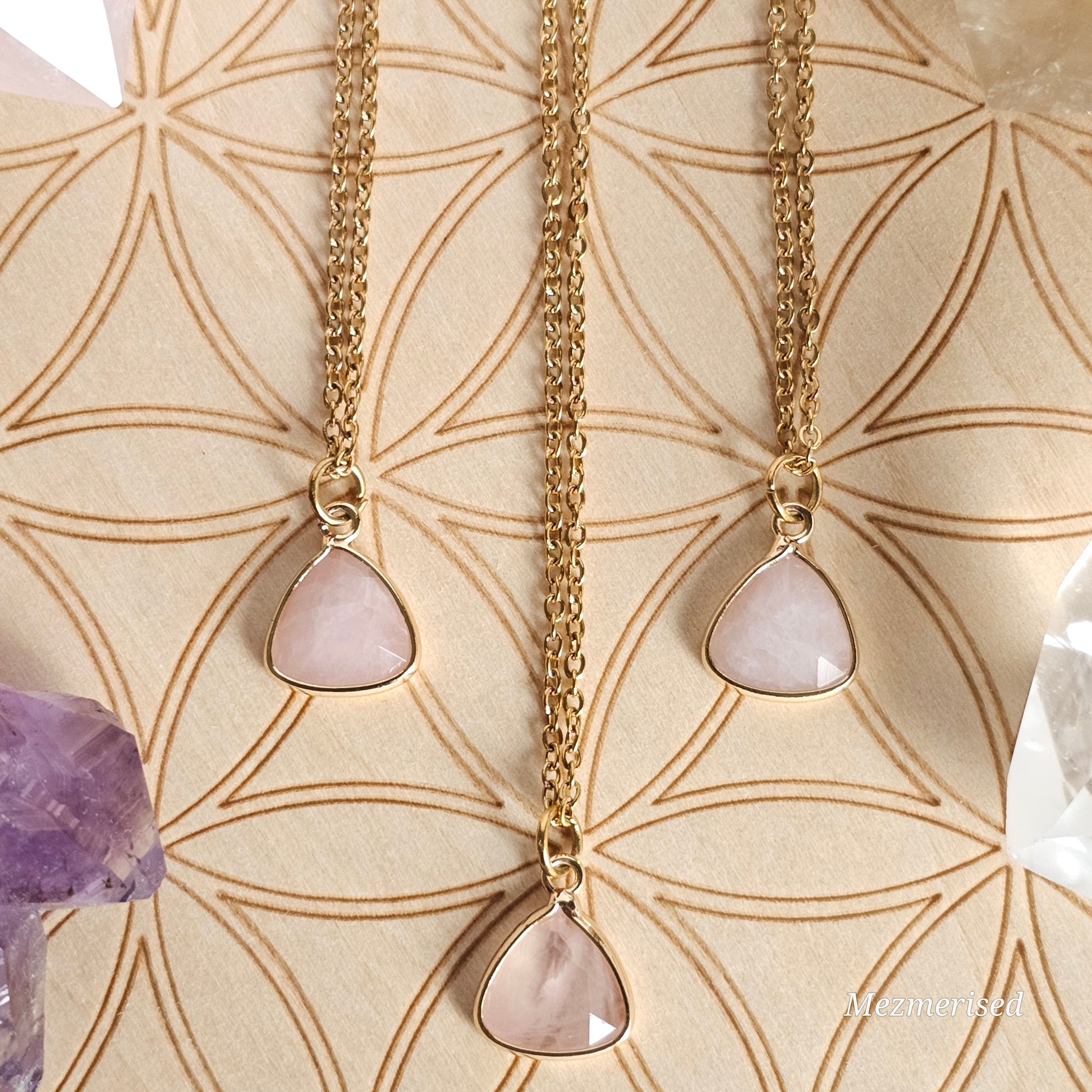 Faceted Rose Quartz trillion pendant suspended from a gold coloured stainless steel chain.