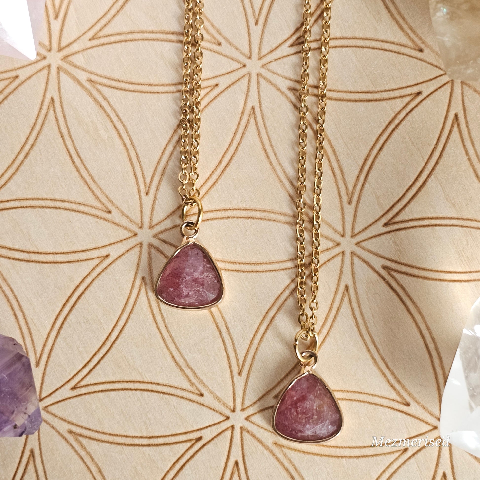 Faceted Strawberry Quartz trillion pendant suspended from a gold coloured stainless steel chain.